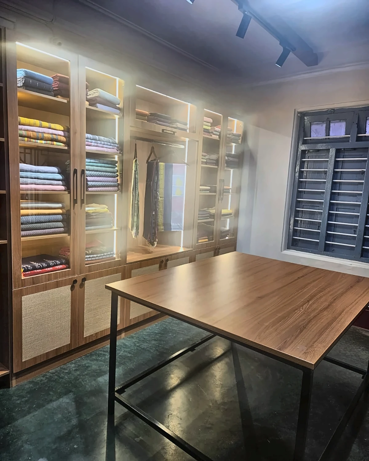 Handloom sarees displayed on studio racks behind a selection table with painted textiles