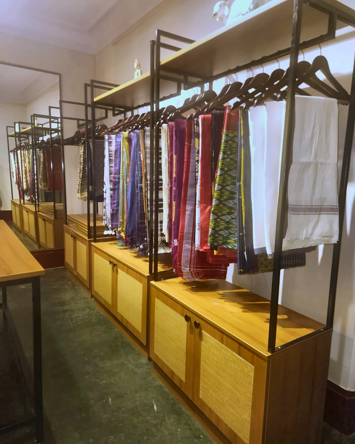 Wide view of the Sutra Kalaa selection room with illuminated saree cabinets and a central selection table